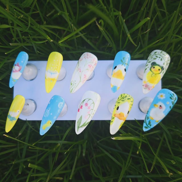 A playful hand-painted duck and floral nail set photographed outdoors